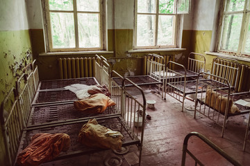 Old broken children beds in kindergarten, nursery school. Destroyed abandoned ghost city Pripyat...