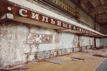School gym in destroyed abandoned ghost city Pripyat ruins after Chernobyl disaster. Exclusion zone, radiation risk, fallout lost town, apocalyptic building. Text in Cyrillic: Strong Brave Deft.