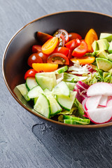 Vegan buddha bowl. Healthy vegetarian salad with cherry tomatoes, cucumber, radish,, avocado and lettuce.