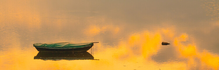 boat laying in water with sunset