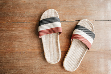 Slipper weave by handmade on wooden floor surface background. Pair of shoe on red and blue colour ready to ware at home. Concept of comfort home relax and holiday free time.