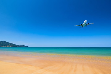 Fototapeta na wymiar Air plane fly over the sand beach and blue sea in Nai Yang beach, Phuket, Thailand