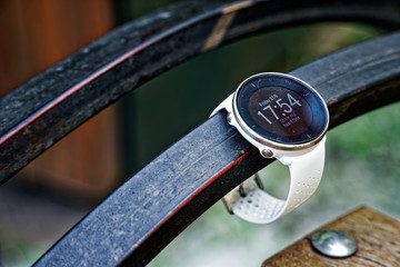 Sport watch for running white color on wooden bench. Fitness watch for tracking daily activity and power training.