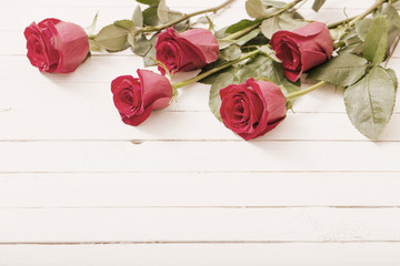  red roses on white wooden background