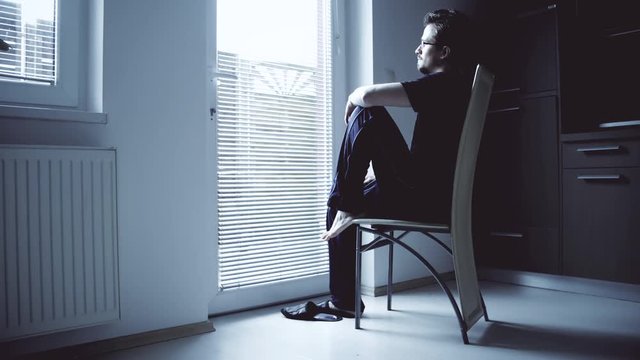 Thinking man at the window sitting and looking out 4K