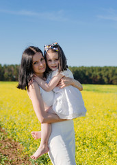 Mom and daughter in field of yellow flowers. mother's day concept