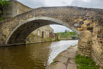 Old stone packhorse bridge  and warehouses on the Leeds and Liverpool Canal, at Dockfield, Shipley on the site of the junction of the meeting with the now defunct Bradford Canal