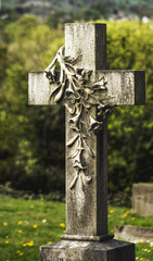 An elegantly carved memorial headstone in Nab Wood Cemetery, Shipley, Yorkshire with lilies cascading down a cross