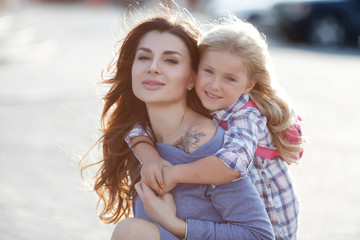 Obraz premium Mother and daughter outdoors in city. playing and having fun. Fashion happy mother and child daughter having fun together in the city.Mother with little charming daughter are joy in the city