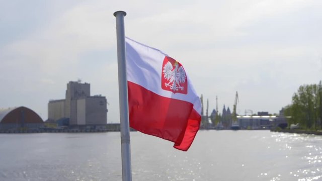 Polish flag with coat of arms on ship waving on wind on industrial background