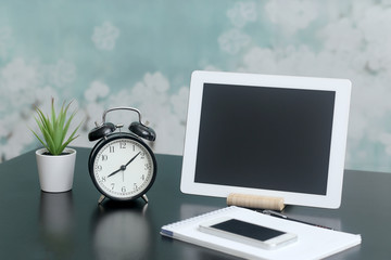 Tablet computer, home plant, notebook, phone, clock on the table. Work at home. Gadgets and electronics.