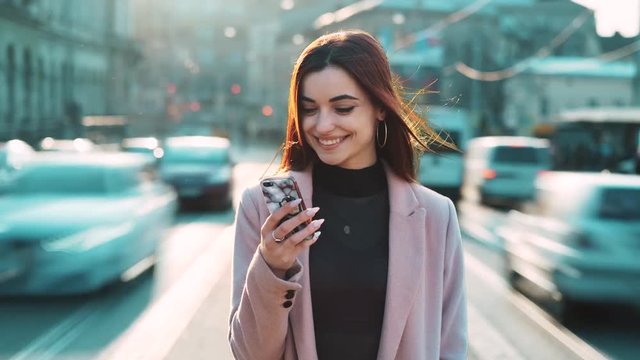 exited pretty european girl with smartphone mobile phone standing in the busy street between moving cars road traffictexting message use application timelapse city slow fast motion