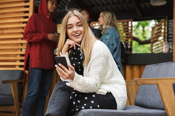 Smiling excited teenager sitting outdoors