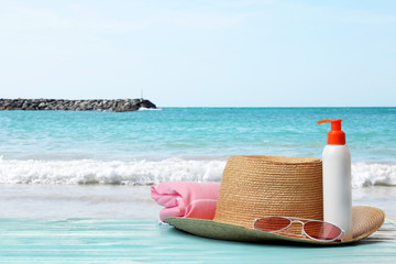 Different stylish beach accessories on pier near sea. Space for text