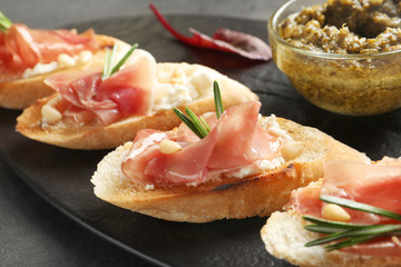 Tasty bruschettas with prosciutto and cream cheese served on table, closeup