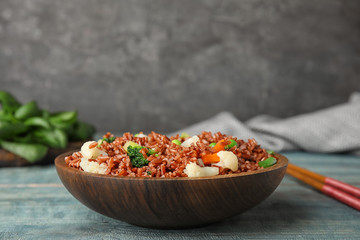 Plate of brown rice with vegetables on table
