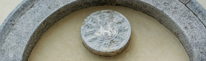JHS Christogram of the stone above the lateral entrance of church of San Francesco, Scutari, Albania