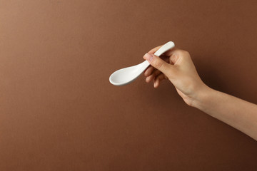 Woman holding empty miso soup spoon on color background, closeup. Space for text