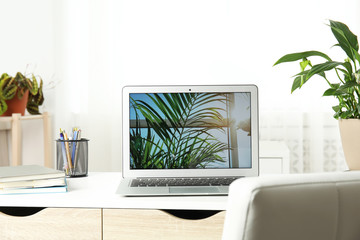Houseplants and laptop on table in office interior