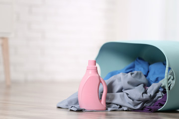 Detergent and laundry basket with dirty clothes on floor indoors. Space for text