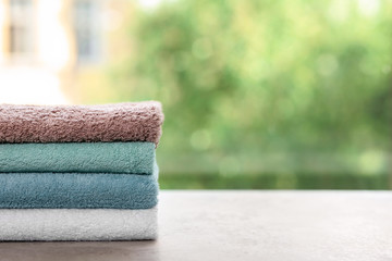 Stack of clean towels on table against blurred background. Space for text