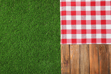 Picnic table with checkered cloth on grass, top view. Space for text