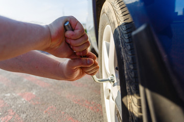 Close-up hands with cylinder wrench unscrew damaged wheel of car. Man changes flat wheel after car breaks down. Wheel balancing, repair and replacement car tires on wheels. Tire installation concept © korchemkin