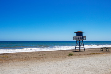 Empty beach with a lifeguard tower and a tennis table at Torre de Benagalbon, Province of Malaga, Andalusia, Spain