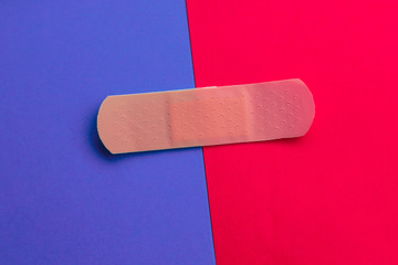 Adhesive bandage or Sticking plaster on a two colored paper background.