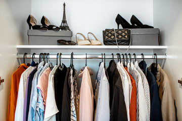 Wardrobe closet full of different clothes and female shoes indoors