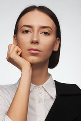 Portrait of a beautiful pacified woman in a white shirt and black jacket. Studio photo session