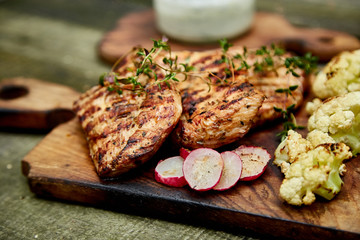 Grilled turkey meat. Steak turkey grill on wooden cutting board with a variety of grilled vegetables on  rustic background  Top view. Flat lay. Copy space..