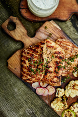 Grilled turkey meat. Steak turkey grill on wooden cutting board with a variety of grilled vegetables on  rustic background  Top view. Flat lay. Copy space..