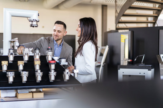 Businessman and businesswoman examining workpieces in factory