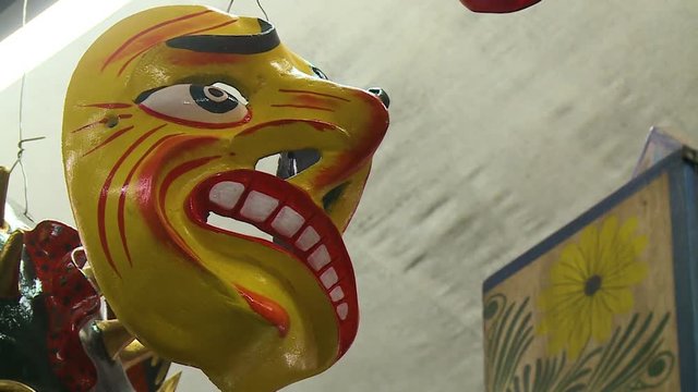 Extreme close-up low-angle still shot of a hanging  Paucartambo traditional dancer's mask painted in bright red and yellow colours, San Blas, Cusco