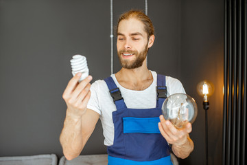 Handyman choosing between energy saving and traditional lightbulb at home