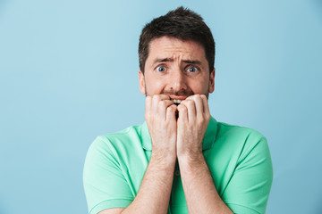 Scared confused young handsome bearded man posing isolated over blue wall background.