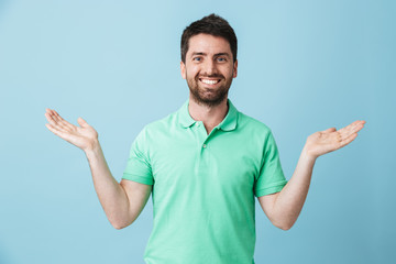 Fototapeta premium Happy young handsome bearded man posing isolated over blue wall background showing copyspace.