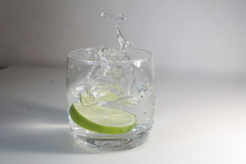 glass of water with green lime and splashes
