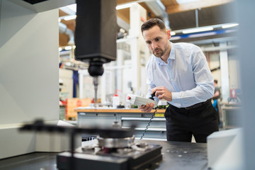 Man operating machine with control in a factory