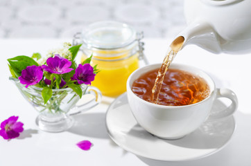 Cup of hot tea with mint and honey on white background. The process of pouring tea. bouquet of...