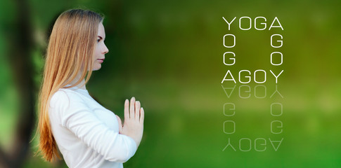 Fototapeta na wymiar young woman in white clothes doing yoga, hands at the heart chakra in front of the chest namaste at sunset, on a blurred lush green background