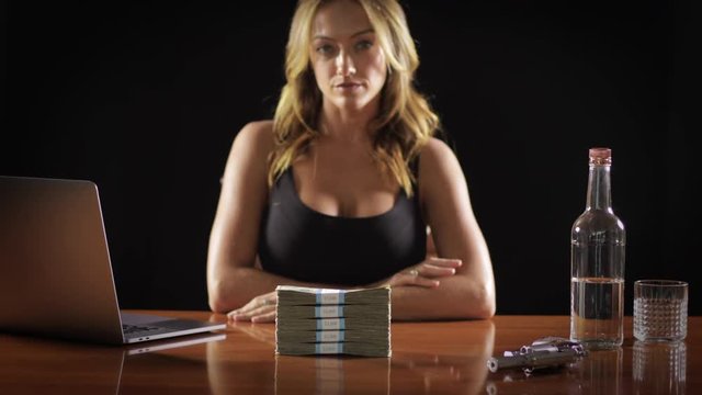 Sexy woman pushes a stack of money accross a table.