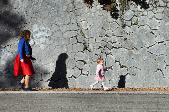 Little girl running with her mother at a stone wall