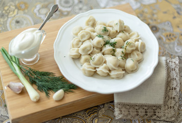 Boiled meat dumplings served with sour cream, garlic and onion. Traditional Russian pelmeni. 