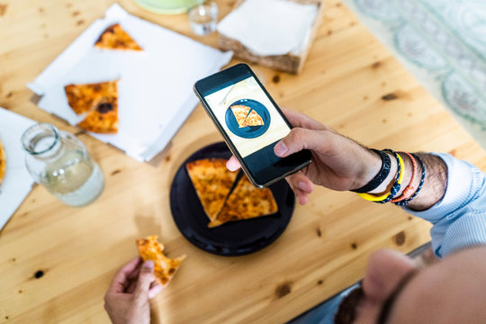 Person taking smartphone picture of a piece of pizza on a plate