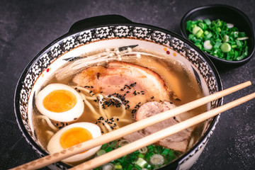 Udon Noodles in Japanese Ramen Soup with Pork, Eggs and Scallion on Dark Background