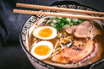 Udon Noodles in Japanese Ramen Soup with Pork, Eggs and Scallion on Dark Background