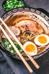 Udon Noodles in Japanese Ramen Soup with Pork, Eggs and Scallion on Dark Background