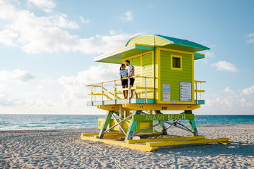 Fototapeta premium Miami South Beach, młoda para mężczyzn i kobiet na plaży podczas wschodu słońca. Miami Beach Floarida